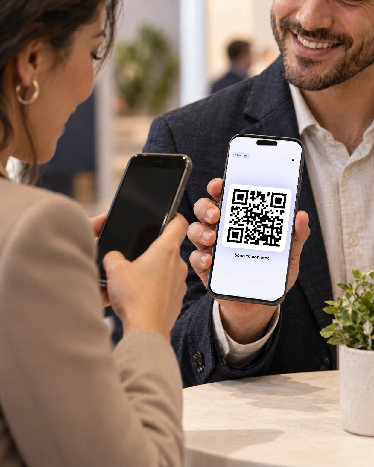 Two people at a conference booth sharing a digital business card between their phones.