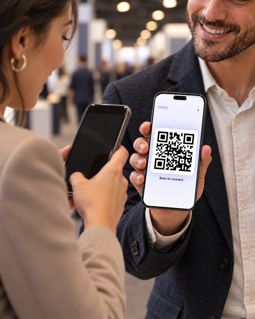 Exchanging contact details with a digital business card on a trade show floor.