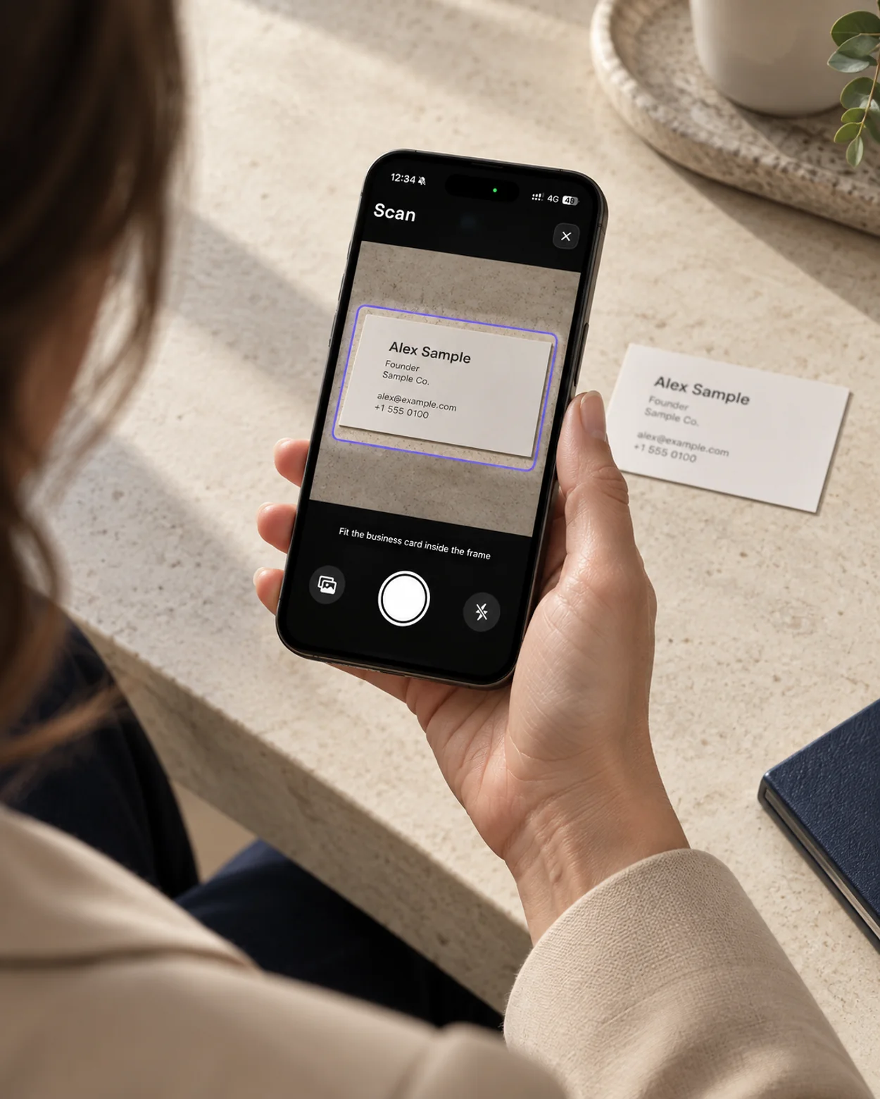 A phone photographing a sample paper business card inside the scanner capture frame.